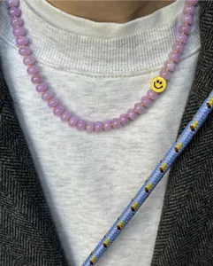 Detalle de collar de cuentas de calcedonia púrpura con perla de cara sonriente amarilla