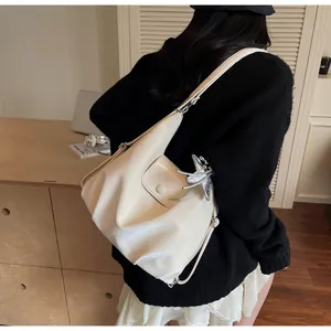 Close-up of cream-colored pleated shoulder bag with silver star charm in lifestyle setting