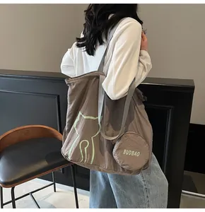 Brown canvas tote bag with cat print and round coin purse shown on a casual model