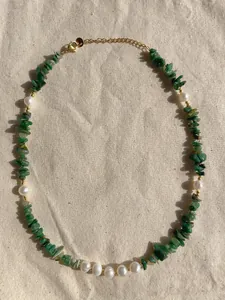 Close-up of handmade necklace with green natural stones, freshwater pearls and gold clasp