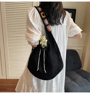 Detail der schwarzen Häkeltasche mit bunten gestrickten Blumen am Schultergurt