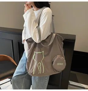 Detail of grey-brown tote bag featuring minimalist cat outline and round coin purse