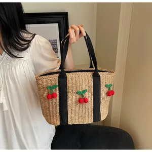 Detailansicht der Strohtasche mit handgefertigten 3D-Kirschen und schwarzen Canvas-Griffen