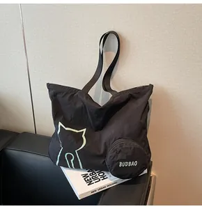 Detail of black nylon tote bag featuring a green cat print and a round coin pouch