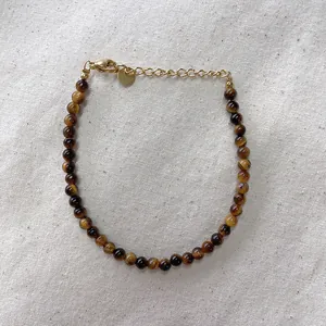 Macro view of beaded bracelet with tiger eye stones and gold lobster clasp detail