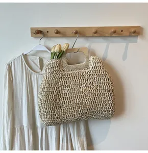 Vue détaillée du sac cabas en paille tissée avec poignées carrées en bois sur crochet