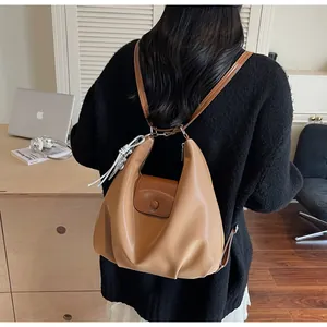 Back view of a model wearing a light brown hobo backpack with soft leather and flap closure