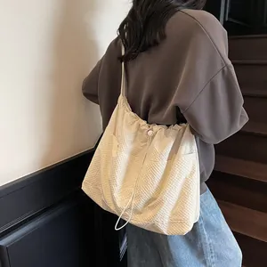 Minimalist beige pleated canvas tote bag with drawstring closure and shoulder straps