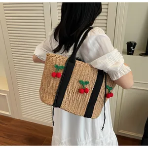 Detail der gewebten Strohtasche mit 3D-Häkelkirschen und schwarzen Schultergurten