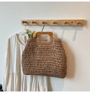 Détail d'un sac de plage en paille tressé à la main avec poignée carrée en bois clair