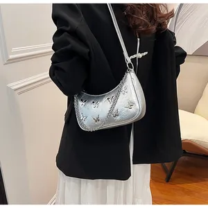 Silver hobo bag with butterfly charms and chain strap shown on a model's shoulder