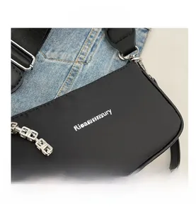 Detail view of black nylon shoulder bag featuring silver metal chain and logo print