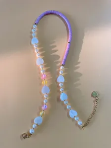 Detail of handmade beaded necklace with purple stones, pearls, and gold heart pendant