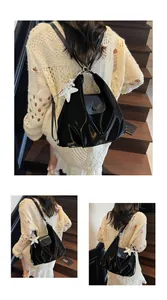 Detail of black glossy hobo bag with silver star charm and sleek pleated design