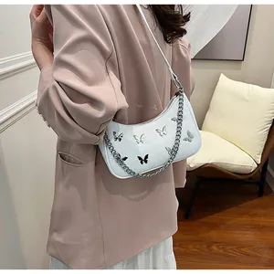Detail of white moon bag featuring silver butterfly studs and chunky metal chain