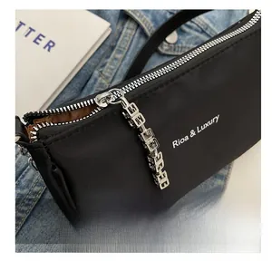 Detailed close-up of a smooth silver zipper on a black nylon handbag with branded logo