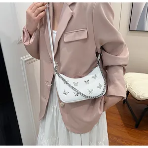 Detail of white crescent shoulder bag with silver butterflies and metal chain strap