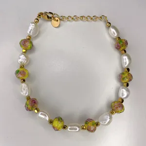 Detailed shot of handmade bracelet with baroque pearls, floral beads, and gold extender chain