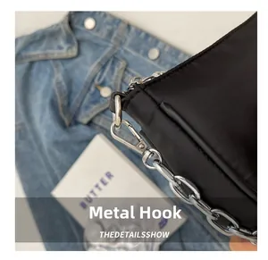 Detail shot of the polished silver hardware hook and metal chain on a black nylon bag