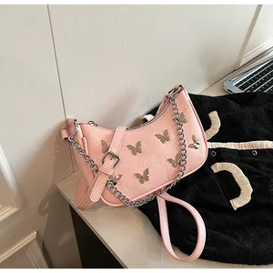 Detailed close-up of pink shoulder bag with silver butterfly accents and chain strap