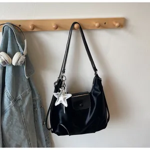 Detail of black satin hobo shoulder bag with silver star charm hanging on wooden hook