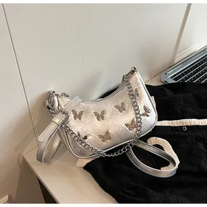Silver metallic underarm bag with butterfly accents and textured pleated finish