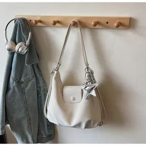 Detail of cream shoulder bag with magnetic flap closure and silver star charm accessory