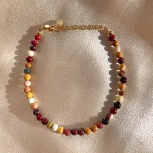 Detail view of colorful natural stone beads and gold adjustable clasp on satin fabric