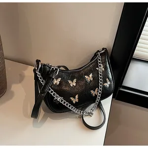 Detail of black pleated faux leather bag with silver butterfly charms and chain strap