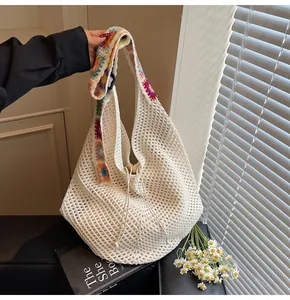 Detail der Häkeltasche mit bunten Blumenriemen und beiger gewebter Netzstruktur
