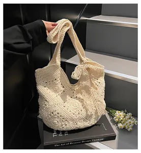 Detail of hand-woven crochet shoulder bag with large bow and intricate hollow pattern