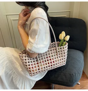 Detail of a woven hollow-out beige handbag with dual handles and floral decor