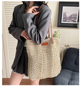 Close-up of handwoven straw tote bag with brown leather handles and YELIYA logo detail