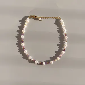 Detail of handmade freshwater pearl bracelet with purple natural stones and gold clasp