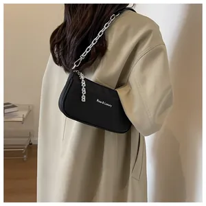 Detailed view of black minimalist underarm bag with silver chain strap and brand lettering