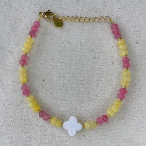 Detailed macro view of beaded bracelet with clover charm and golden metal extension chain