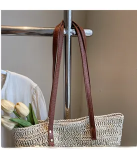 Detail of beige woven tote bag showing durable brown leather straps and brand patch