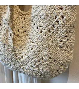 Close-up of floral crochet patterns and wave edge on the handmade cream woven bag