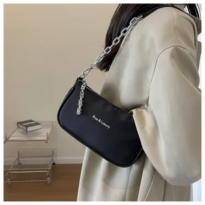 Detail of black nylon shoulder bag with silver chain strap and metal logo pendant