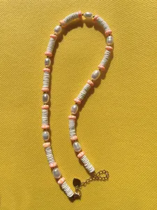 Detail of beaded necklace with freshwater pearls, heishi beads and golden heart clasp