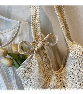 Close-up of handmade off-white crochet shoulder bag with a large woven bow detail