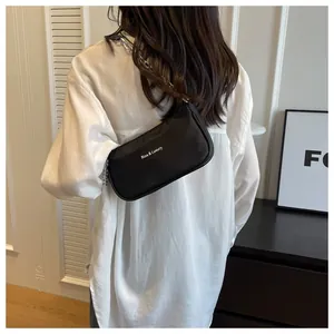 Detail of black nylon shoulder bag with thick silver chain strap on white shirt