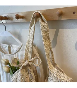 Close-up of beige hand-woven shoulder bag featuring a decorative knitted side bow detail