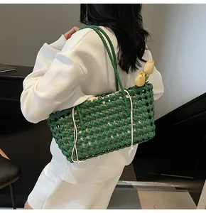 Close-up of green woven bucket bag with hollow mesh texture and white drawstring pouch