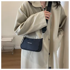 Model wearing a black nylon crossbody bag with silver hardware and a chain detail