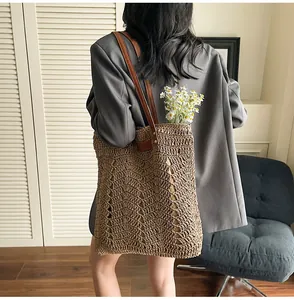 Detail of hand-woven straw tote bag with brown leather straps and wave pattern texture