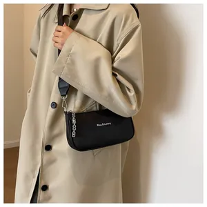 Detail of black nylon crossbody bag with silver metal chain and luxury logo text