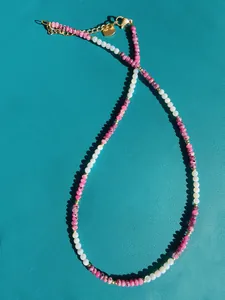 Macro detail of natural stone and freshwater pearl beaded necklace with gold heart charm