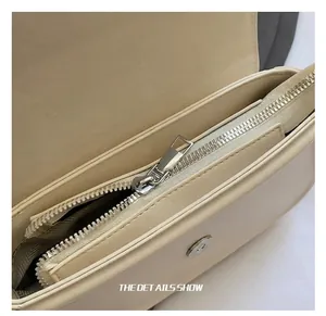 Gros plan du sac à main crème en cuir avec fermeture éclair argentée et boucle magnétique