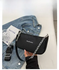 Detail of black crescent shoulder bag with silver chain and white logo on blue denim